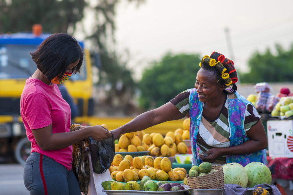 African American female in a protective face mask shopping for fruit at a market